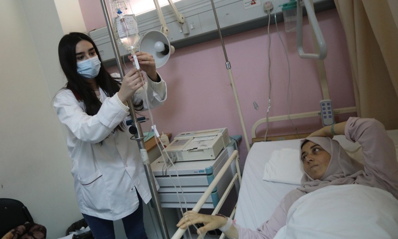 A nurse adjusts the dripping speed of the drip bottle for a female patient in a hospital in Beirut, capital of Lebanon, on March 27, 2021.(Photo: Xinhua)