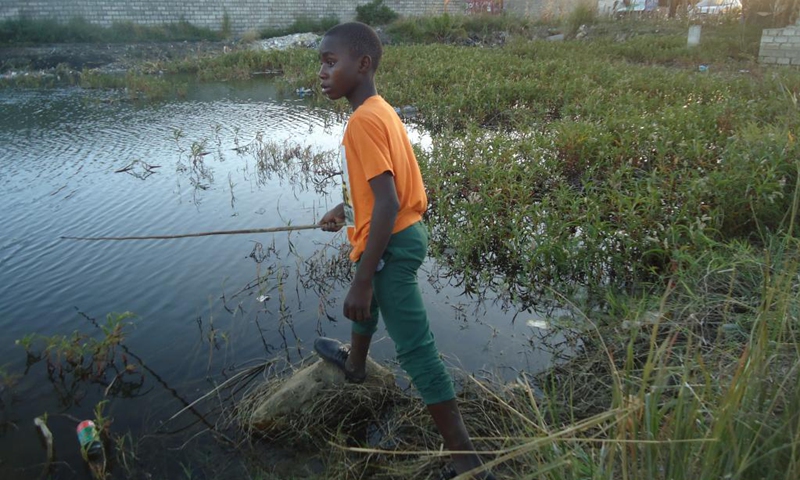 A boy fishes at a popular dam in Misisi compound, a slum in Zambia's capital Lusaka on April 12, 2021.(Photo: Xinhua)