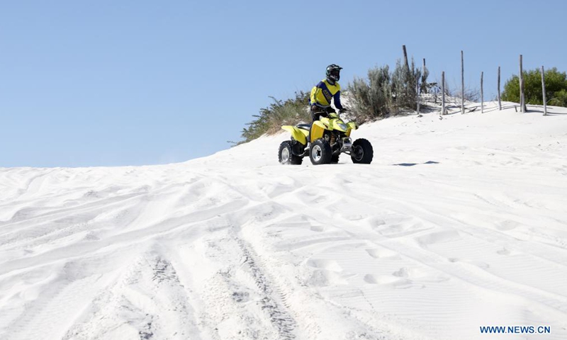 A person rides a quad bike on dunes at the Witzands Aquifer Nature Reserve, nothern Cape Town, South Africa, on April 23, 2021. The Witzands Aquifer Nature Reserve is famous for the Atlantis dunes which cover 500 hectares of the reserve. It is a flora and fauna-rich landscape. Below the surface, a large underground natural aquifer supplies the surrounding communities with water. The reserve offers activities such as off-road driving, quad biking and sand boarding.Photo:Xinhua