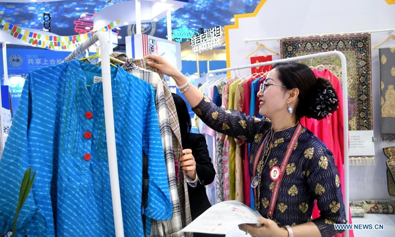 An exhibitor introduces products to a guest during the 2021 Shanghai Cooperation Organization (SCO) International Investment and Trade Expo in Qingdao, east China's Shandong Province, April 26, 2021. The 2021 SCO International Investment and Trade Expo & SCO Qingdao Forum on Local Economic and Trade Cooperation opened here on Monday.(Photo:Xinhua)