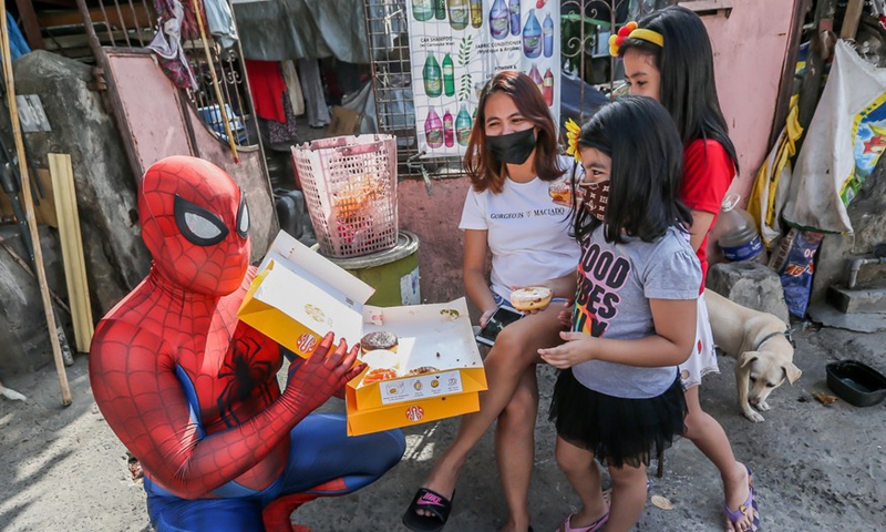 A man dressed as Spider-Man distributes donuts to children affected by the COVID-19 lockdown outside their home in Manila, the Philippines on April 27, 2021.Photo:Xinhua