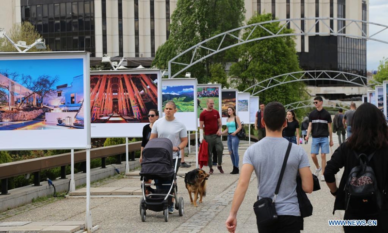 People walk past display panels of a photo exhibition entitled Cases of Poverty Alleviation through Tourism in China in Sofia, Bulgaria, on May 5, 2021. The photo exhibition entitled Cases of Poverty Alleviation through Tourism in China opened here on Wednesday.(Photo: Xinhua)