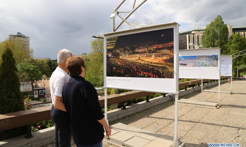 People look at a display panel at a photo exhibition entitled Cases of Poverty Alleviation through Tourism in China in Sofia, Bulgaria, on May 5, 2021. The photo exhibition entitled Cases of Poverty Alleviation through Tourism in China opened here on Wednesday.(Photo: Xinhua)