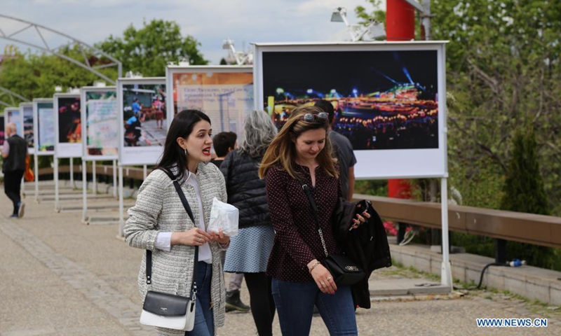 People walk past display panels of a photo exhibition entitled Cases of Poverty Alleviation through Tourism in China in Sofia, Bulgaria, on May 5, 2021. The photo exhibition entitled Cases of Poverty Alleviation through Tourism in China opened here on Wednesday.(Photo: Xinhua)