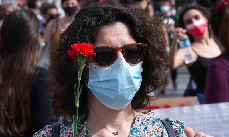 A woman holding a flower is seen among demonstrators, in Athens, Greece, on May 6, 2021. Thousands of protesters hit the streets of Athens and other major cities on Thursday in rallies organized by labor unions to mark a belated May Day in Greece. Photo:Xinhua