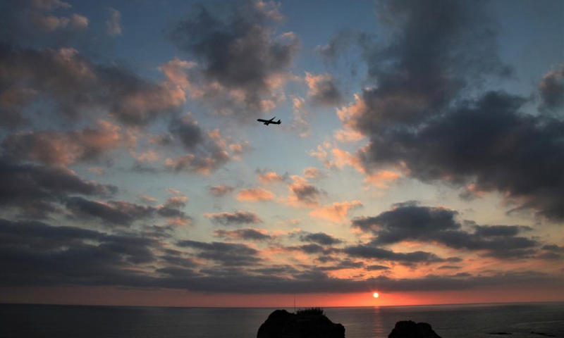 A plane flies over Raouche Rocks at sunset in Beirut, Lebanon, on May 13, 2021.Photo:Xinhua