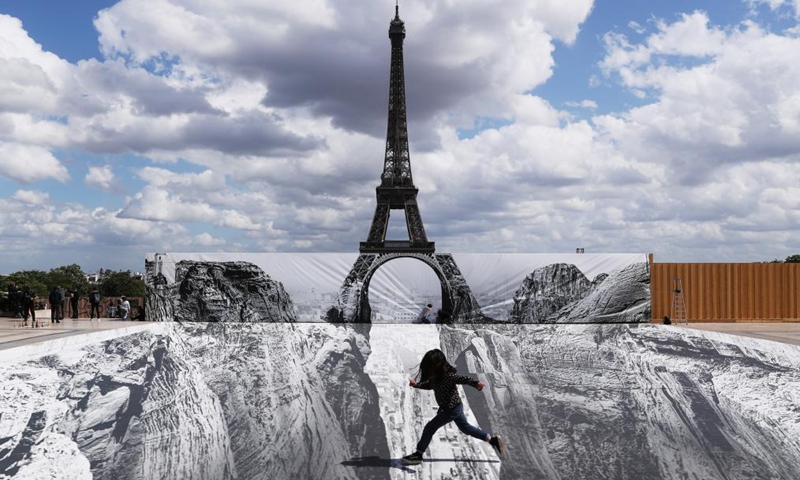 A girl poses for photos on the Trocadero square near the Eiffel Tower where French artist and photographer known as JR set his artwork, in Paris, France, on May 21, 2021. (Xinhua/Gao Jing)