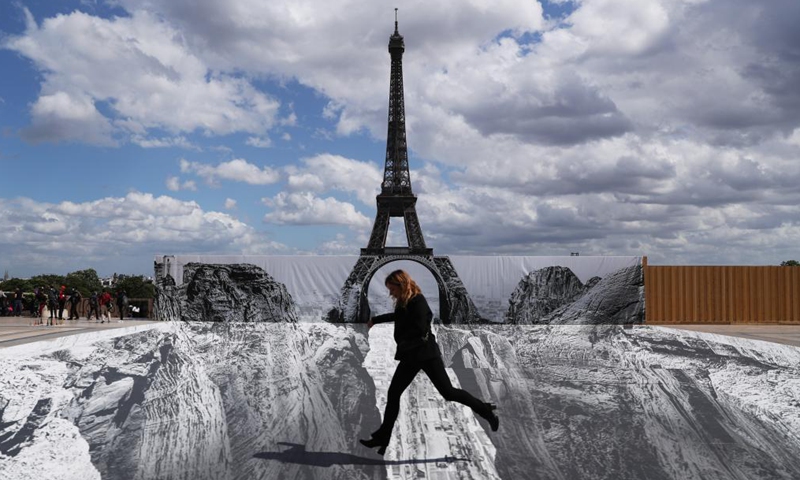 A woman poses for photos on the Trocadero square near the Eiffel Tower where French artist and photographer known as JR set his artwork, in Paris, France, on May 21, 2021. (Xinhua/Gao Jing)