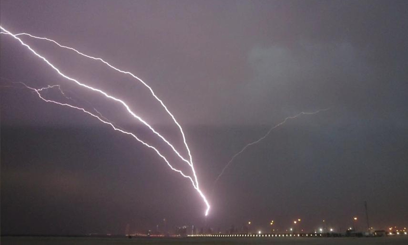 Photo taken on May 24, 2021 shows lightning bolts over the skyline of Kuwait City, Kuwait. (Photo by Asad/Xinhua)