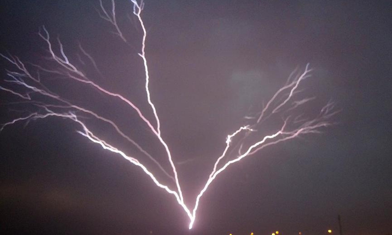 Photo taken on May 24, 2021 shows lightning bolts over the skyline of Kuwait City, Kuwait. (Photo by Asad/Xinhua)