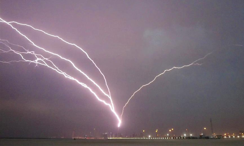 Photo taken on May 24, 2021 shows lightning bolts over the skyline of Kuwait City, Kuwait. (Photo by Asad/Xinhua)