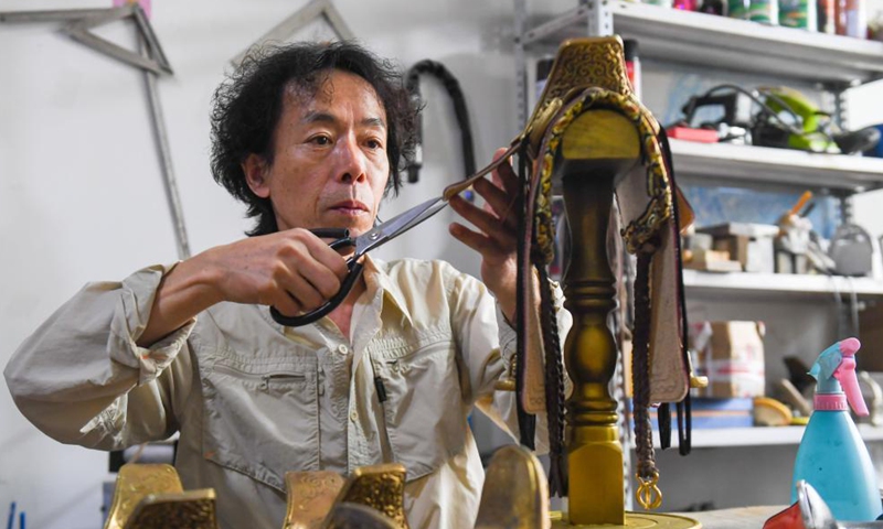 Xilinhu makes a saddle-shaped handicraft at his workshop in Xilinhot, north China's Inner Mongolia Autonomous Region, May 26, 2021. Horse riding, archery and wrestling are called men's three skills of the Mongolian ethnic group. Since 2005, handicraftsman Xilinhu of the Mongolian ethnic group has involved the cultural symbols of saddle, bow and arrow and wrestling costume into handicrafts making to promote traditional culture of the ethnic group.  Photo: Xinhua