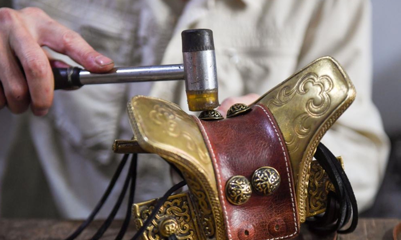 Xilinhu makes a saddle-shaped handicraft at his workshop in Xilinhot, north China's Inner Mongolia Autonomous Region, May 26, 2021. Horse riding, archery and wrestling are called men's three skills of the Mongolian ethnic group. Since 2005, handicraftsman Xilinhu of the Mongolian ethnic group has involved the cultural symbols of saddle, bow and arrow and wrestling costume into handicrafts making to promote traditional culture of the ethnic group.  Photo: Xinhua