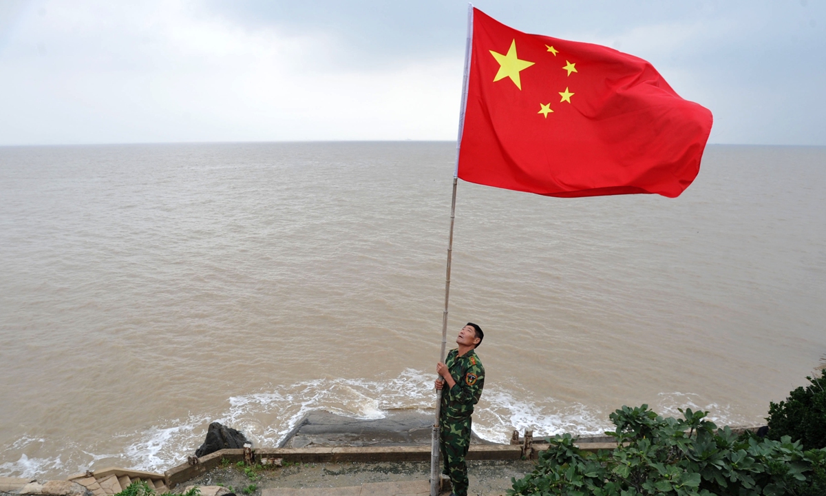 Wang Jicai raises the national flag on the island. Photo: VCG