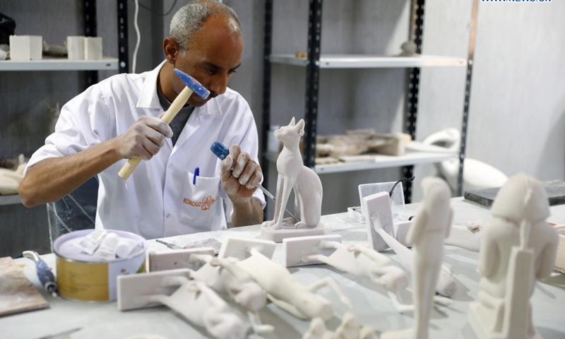 A sculptor works on a replica of an ancient Egyptian statue of cat goddess Bastet at Konouz Egypt Replica Treasures in Qalyubia, Egypt, on May 25, 2021. Dozens of designers, sculptors, painters and workers, were busy producing replicas of ancient Egyptian artifacts at Konouz Egypt Replica Treasures, the first factory in Egypt and the Middle East for producing replicas of historical Egyptian antiquities. Photo:Xinhua 