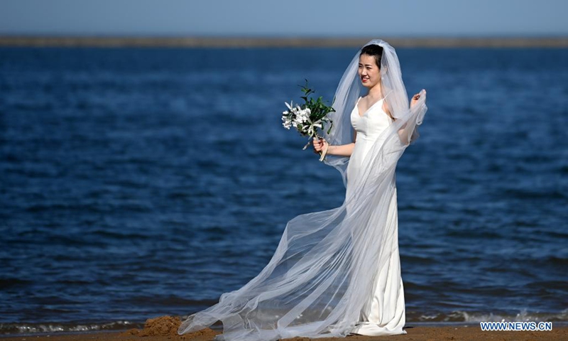 A woman in wedding dress pose for photos at an artificial beach resort at Dongjiang Port in the Binhai New Area of north China's Tianjin, June 5, 2021. Photo: Xinhua 