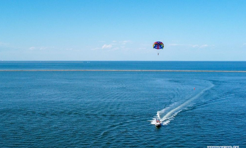 A tourist tries out paragliding at a beach resort at the Dongjiangwan scenic area in the Binhai New Area of north China's Tianjin, June 5, 2021. Photo: Xinhua 