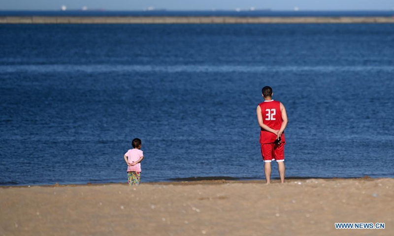 A man and a child look at the sea at an artificial beach resort at Dongjiang Port in the Binhai New Area of north China's Tianjin, June 5, 2021. Photo: Xinhua 