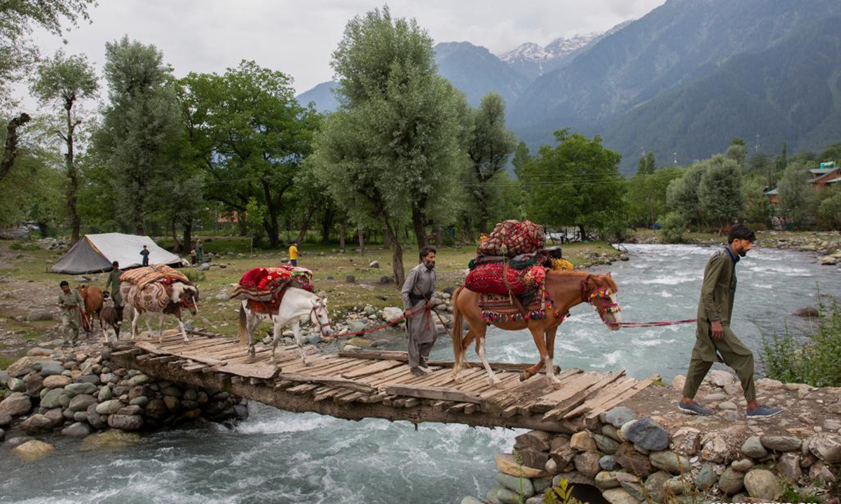 Nomads cross a bridge with horses in Pahalgam village, about 90 km south of Srinagar city, the summer capital of Indian-controlled Kashmir, June 20, 2021. The nomadic tribe known as Bakerwals has begun the seasonal migration towards upper reaches of Indian-controlled Kashmir in the wake of the rising temperatures in plains. (Xinhua/Javed Dar)