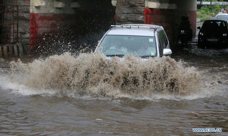 Vehicles run on a water-logged street after a heavy rainfall in Bhopal, capital of India's Madhya Pradesh state, June 22, 2021. (Str/Xinhua)