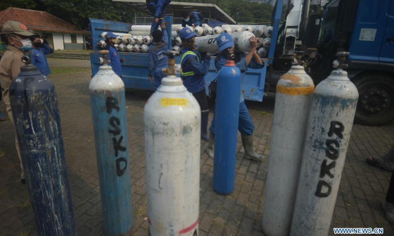 Workers unload oxygen cylinders from a truck at a temporary oxygen refilling station in Jakarta, Indonesia, July 5, 2021. (Photo: Xinhua)