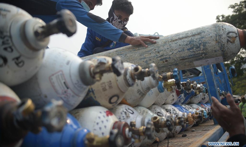 Workers unload oxygen cylinders from a truck at a temporary oxygen refilling station in Jakarta, Indonesia, July 5, 2021. (Photo: Xinhua)