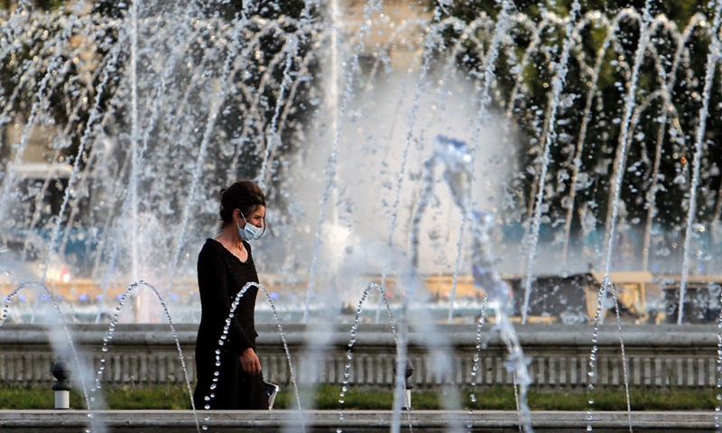 A woman walks past a fountain during a hot day in downtown Bucharest, Romania, on July 28, 2021.Photo:Xinhua