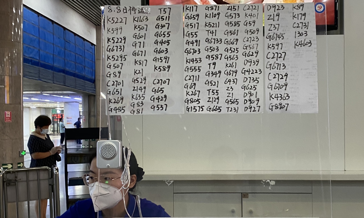 A conductor sits in front of a handwritten bulletin of timetables inside a ticket office of the Beijing West Railway Station on Sunday. A total of 105 departure trains from Beijing West Railway Station were suspended due to continuous heavy rainfall and epidemic prevention and control order covering many parts of the country, railway authority said. Photo: VCG