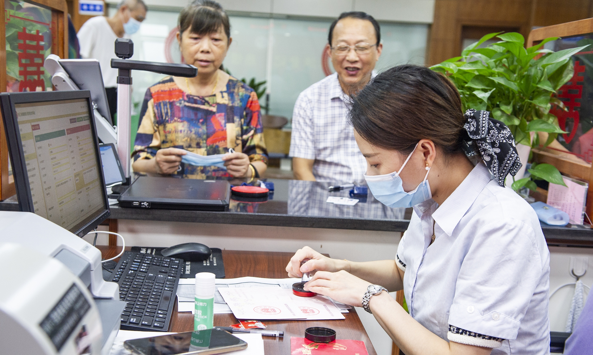  A staff member at the Shangyu district's Civil Affairs Bureau's marriage registration office in Shaoxing, East China's Zhejiang Province handles an application for a replacement marriage certificate for an elderly couple on Thursday. Photo: VCG