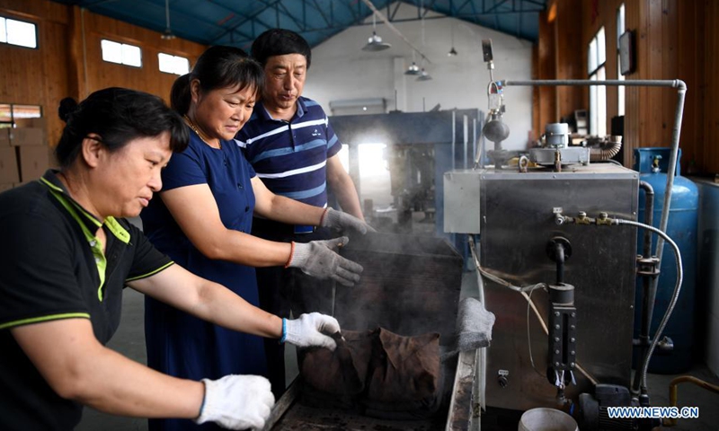 Workers make Yixian dark tea artwork at a studio in Yixian County, east China's Anhui Province, July 30, 2021.Photo:Xinhua