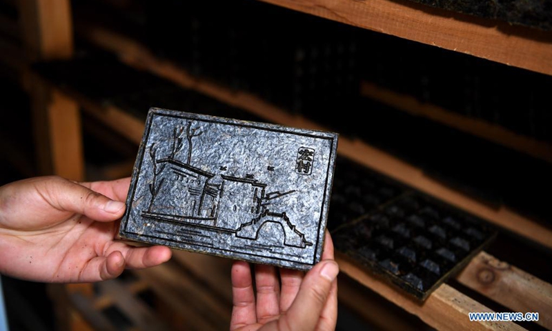 A worker checks a Yixian dark tea artwork at a studio in Yixian County, east China's Anhui Province, July 30, 2021.Photo:Xinhua