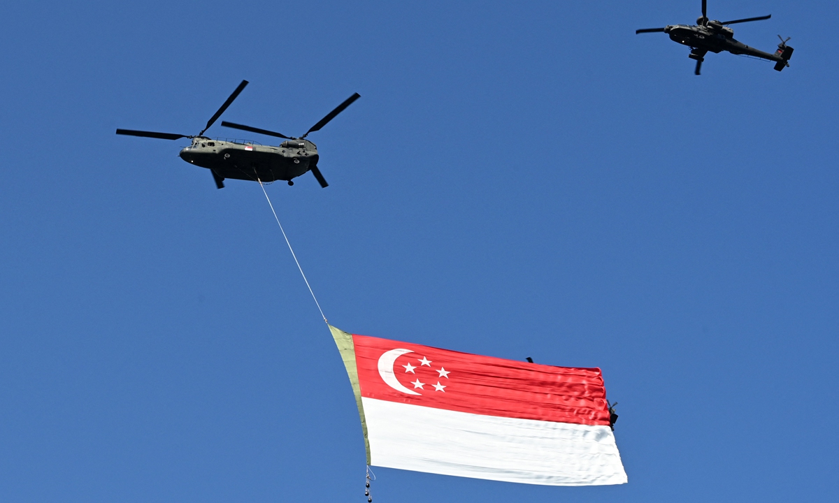 A Republic of Singapore Air Force Chinook helicopter (left) is escorted by an Apache helicopter over the city as they parade the Singapore flag to mark the country's 56th National Day in Singapore on Monday. Photo: AFP