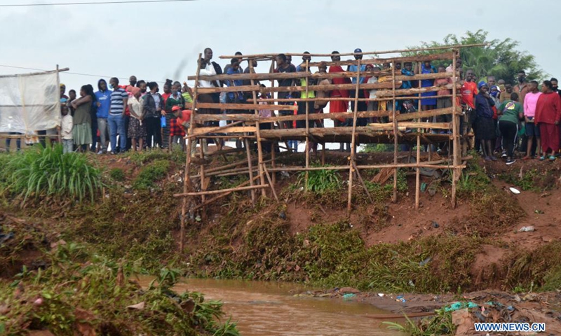 People are seen standing on a temporary podium in the wake of flood triggered by heavy rain in Kampala, Uganda, Aug. 9, 2021.(Photo: Xinhua)