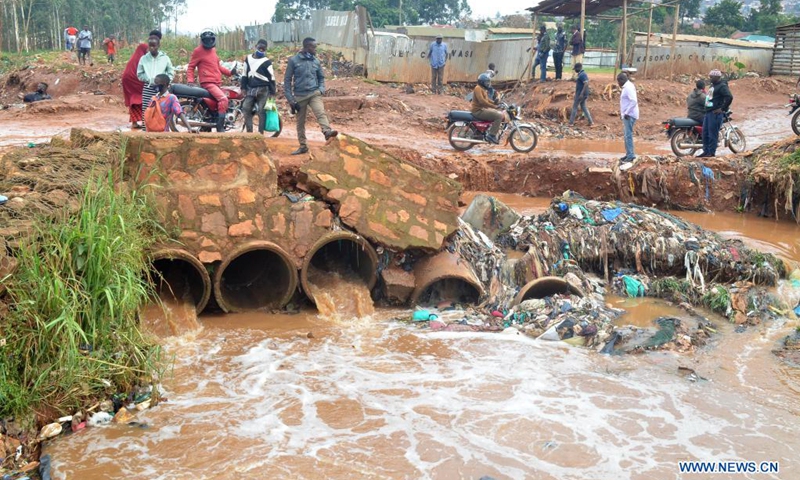 People stand on a damaged bridge in the wake of flood triggered by heavy rain in Kampala, Uganda, Aug. 9, 2021.(Photo: Xinhua)