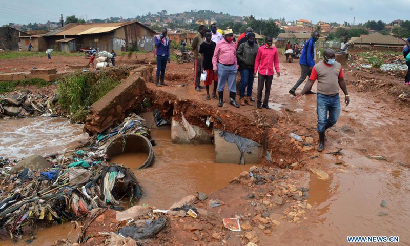 People walk past a damaged public road in the wake of flood triggered by heavy rain in Kampala, Uganda, Aug. 9, 2021. (Photo: Xinhua)