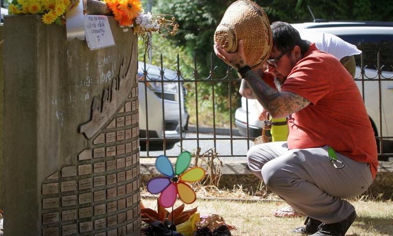 An indigenous man looks at names of the missing children that carved on a memorial at the site of the former St. Paul Indian Residential School in North Vancouver, British Columbia, Canada, on Aug. 10, 2021. Three British Columbia First Nations said they will work together to investigate the disappearance of indigenous children at the site of the former St. Paul's Indian Residential School in North Vancouver on Tuesday.(Phhoto: Xinhua)