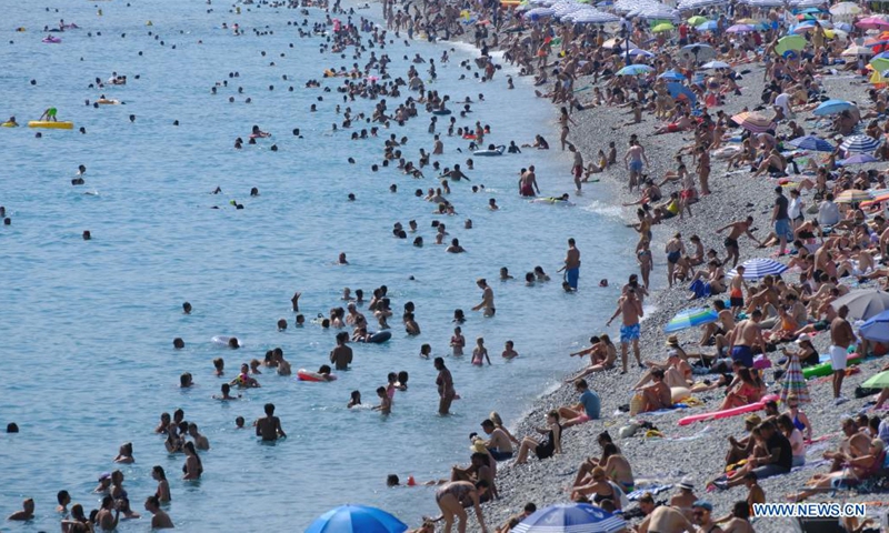 People enjoy leisure time on a beach during hot weather in Nice, France, Aug. 14, 2021. (Photo by Serge Haouzi/Xinhua)