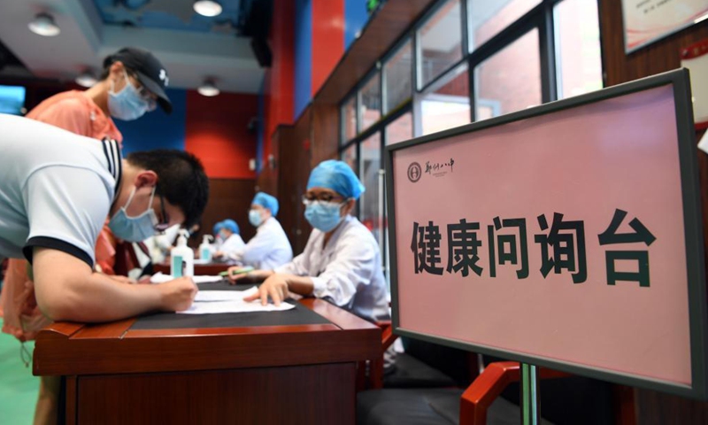 Medical workers explain the precautions for COVID-19 vaccination to students at a vaccination site in a middle school in Zhengzhou, central China's Henan Province, Aug. 19, 2021. Zhengzhou recently started COVID-19 vaccination for minors aged between 12 and 17.Photo:Xinhua