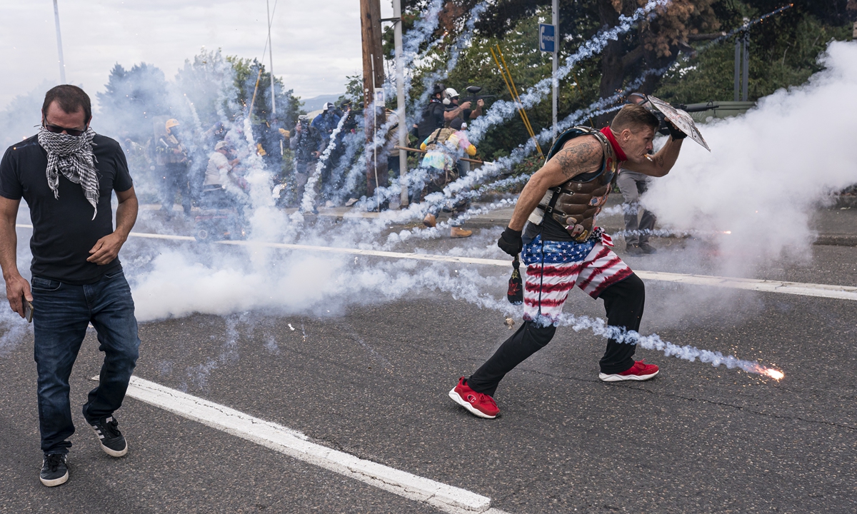 Far-right extremists react to exploding fireworks thrown by left-wing counter protesters on Sunday in Portland, Oregon. The Proud Boys and other far-right extremists fought with anti-fascist activists in Portland on the anniversary of a similar fight in 2020 ahead of the US presidential election. Photo: VCG