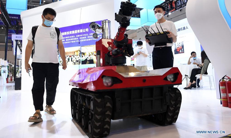 A staff member (R) displays a robot for fire fighting and detection at the Smart China Expo in Chongqing, southwest China, Aug. 23, 2021. The Smart China Expo 2021 opened in Chongqing on Monday, with more than 600 enterprises participating in the exhibition online and offline.(Photo: Xinhua)