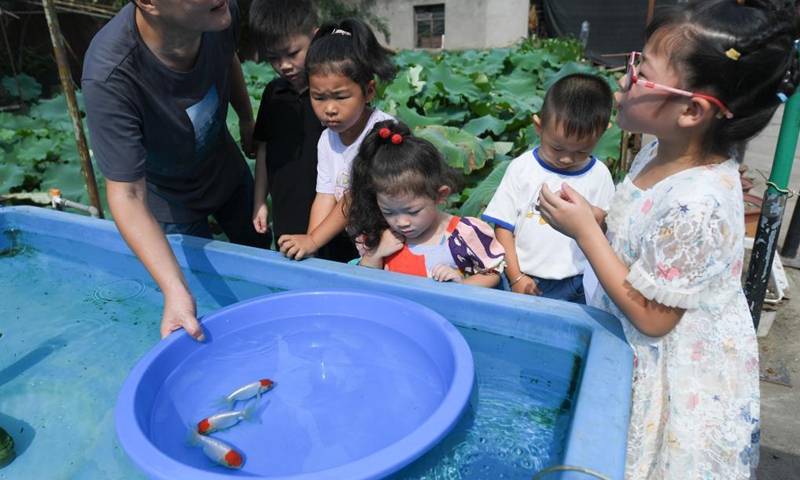 Gao Feng (1st L) explains as children look at the goldfish he breeds in his yard, Shaoxing City, east China's Zhejiang Province, Aug. 24, 2021. Gao Feng, a 43-year-old goldfish enthusiast, has been raising goldfish for nearly 20 years in his yard on the outskirts of Shaoxing City. Now his breeding base can reproduce nearly 1,000 high-quality goldfish every year.(Photo: Xinhua)