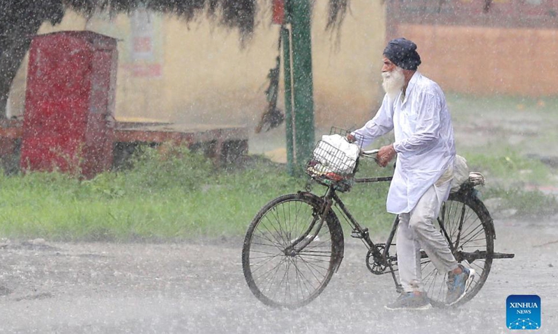 A man walks with his bike in a heavy rain in Amritsar district of India's northern state Punjab, Sept. 8, 2021.Photo:Xinhua