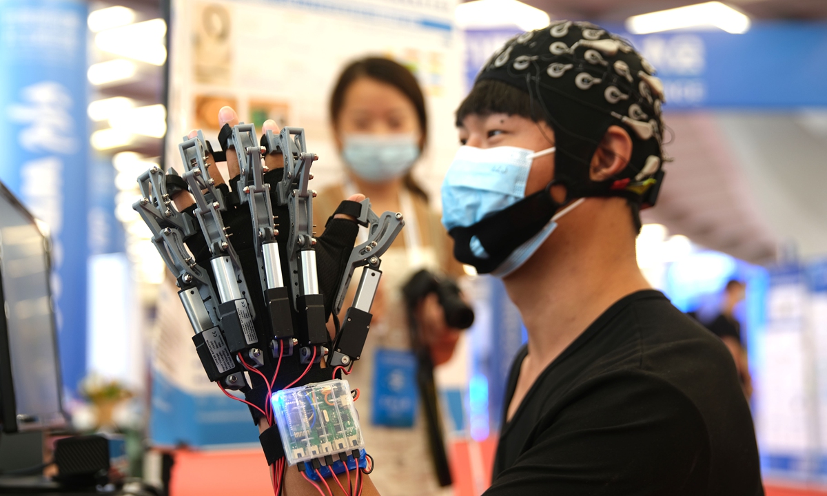 A visitor tries out a mechanical hand used for rehabilitation at the 2021 World Robot Conference on Sunday. China's robot industry underwent rapid growth in the past few years, with China accounting for 44 percent all industrial robot installations in 2020, according to a report by the Xinhua News Agency. Photo: VCG