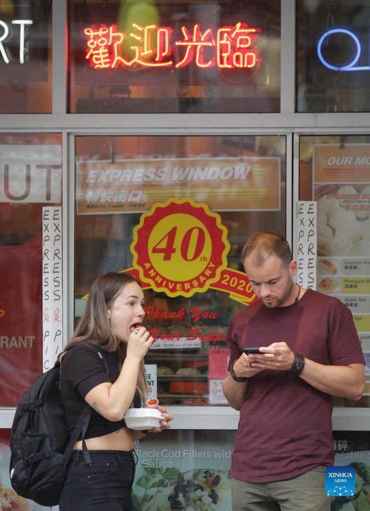 People enjoy food during the Light Up Chinatown event at Chinatown in Vancouver, British Columbia, Canada, Sept. 11, 2021. The two-day event hosted by Chinatown Business Improvement Association featuring live entertainment, food trucks, lights and decorations. The organizer wishes to bring back tourists and shoppers as the businesses are impacted by the COVID-19 pandemic and anti-Asian hate crimes over the past months.Photo: Xinhua