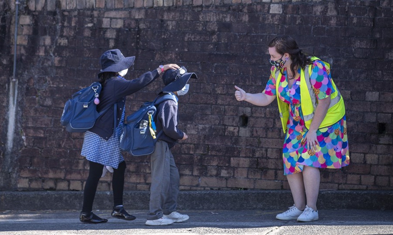 A teacher welcomes students outside a primary school in Sydney, Australia, on Oct. 18, 2021.(Photo: Xinhua)