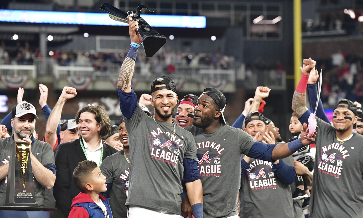 Atlanta Braves MVP Eddie Rosario holds the NL championship trophy alongside his son Lucas after defeating the Los Angeles Dodgers in Game 6 of the MLB NLCS at Truist Park on Saturday, October 23, 2021 in Atlanta, Georgia. Photo: IC