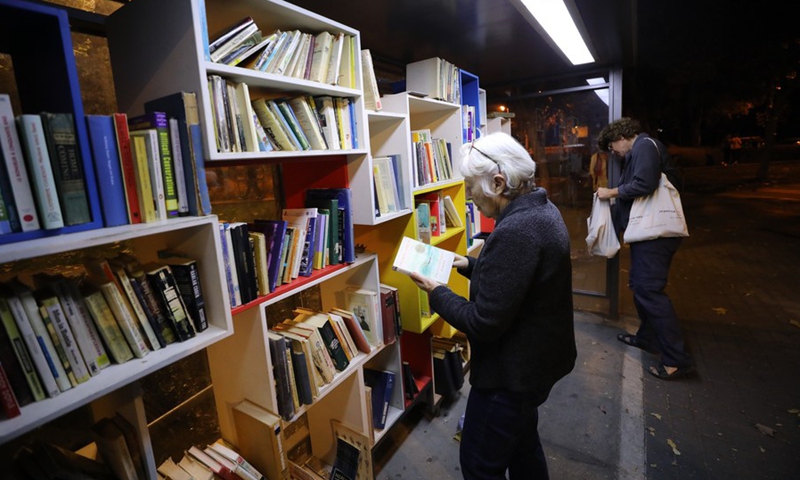 A woman is seen reading a book at a street library in Jerusalem, on Nov. 8, 2021.(Photo: Xinhua)
