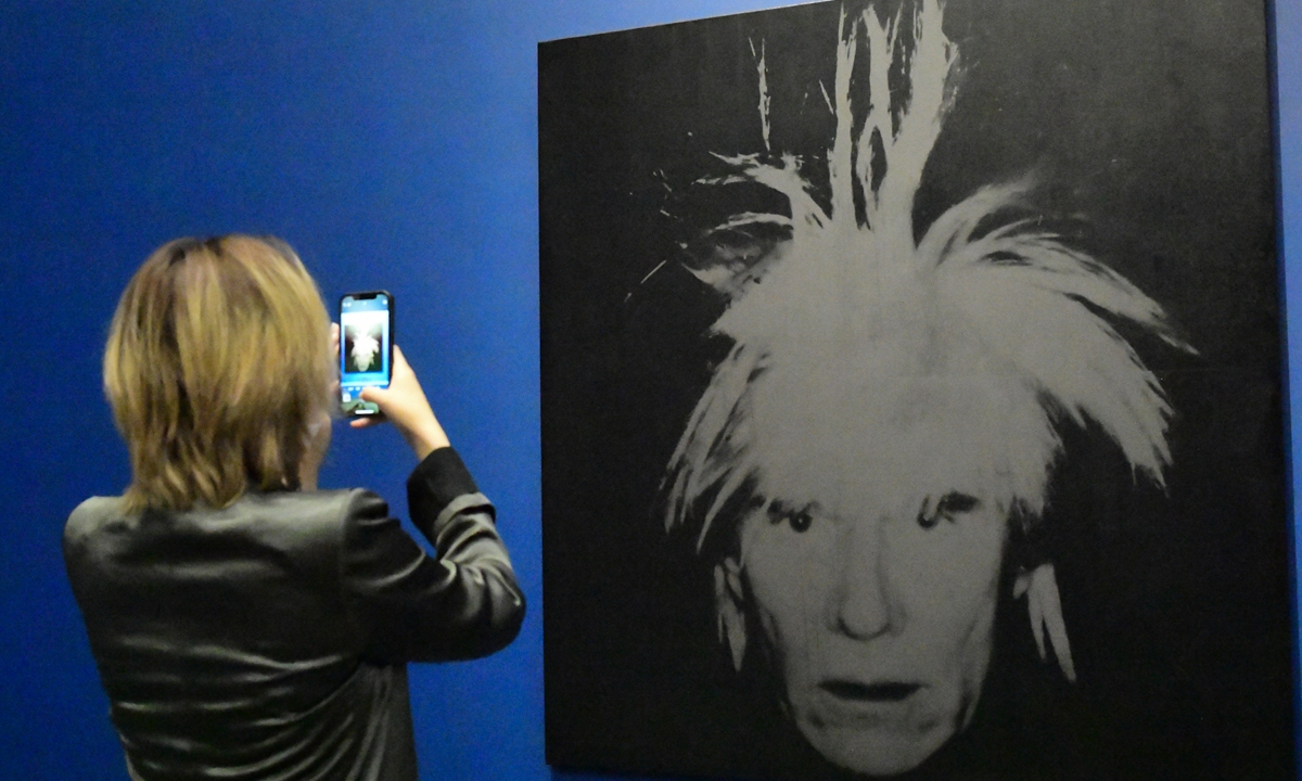 A visitor snaps a photo at an Andy Warhol exhibition in Beijing. Photo: VCG