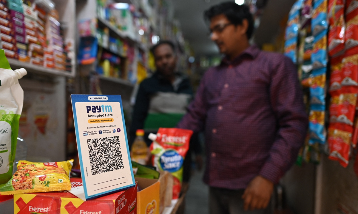 A man (right) shops at a grocery store where a QR code for Paytm, an Indian cellphone-based digital payment platform, is displayed in New Delhi, India on Thursday. Photo: AFP