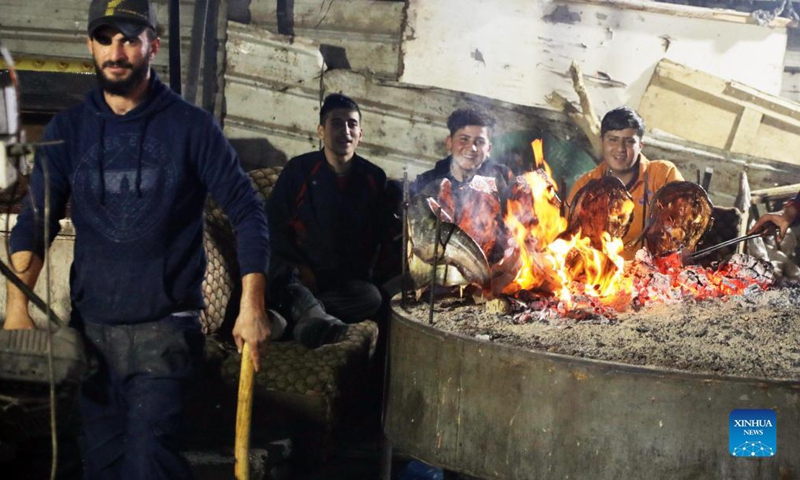 Young people wait for their grilled fish at a stall at the al-Midan market in Mosul, Iraq, Nov. 29, 2021. The market resumed running after its reconstruction and the removal of debris of the destruction by the military operations carried out by the Iraqi forces to expel the militants of the extremist Islamic State (IS) group. (Xinhua/Khalil Dawood)